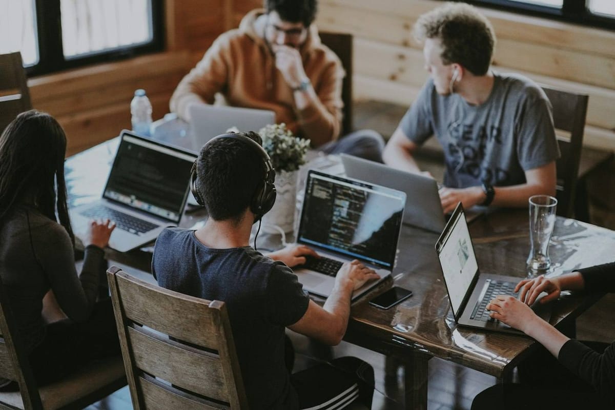 Un equipo trabajando junto en una mesa de madera con portátiles